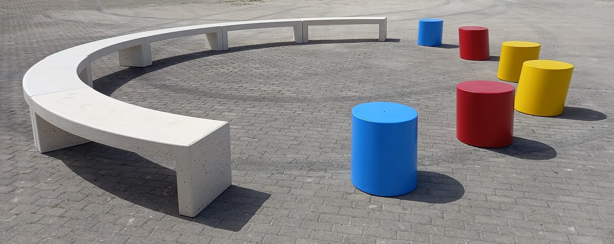 Composizione panche semicircolari in cemento Modus e cilindri pouff Slitt colorati ideali per parchi gioco